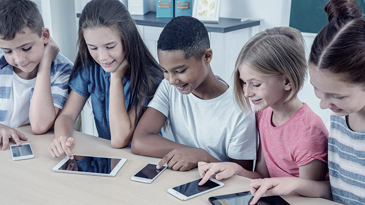 A mixed group of children looking at smart devices